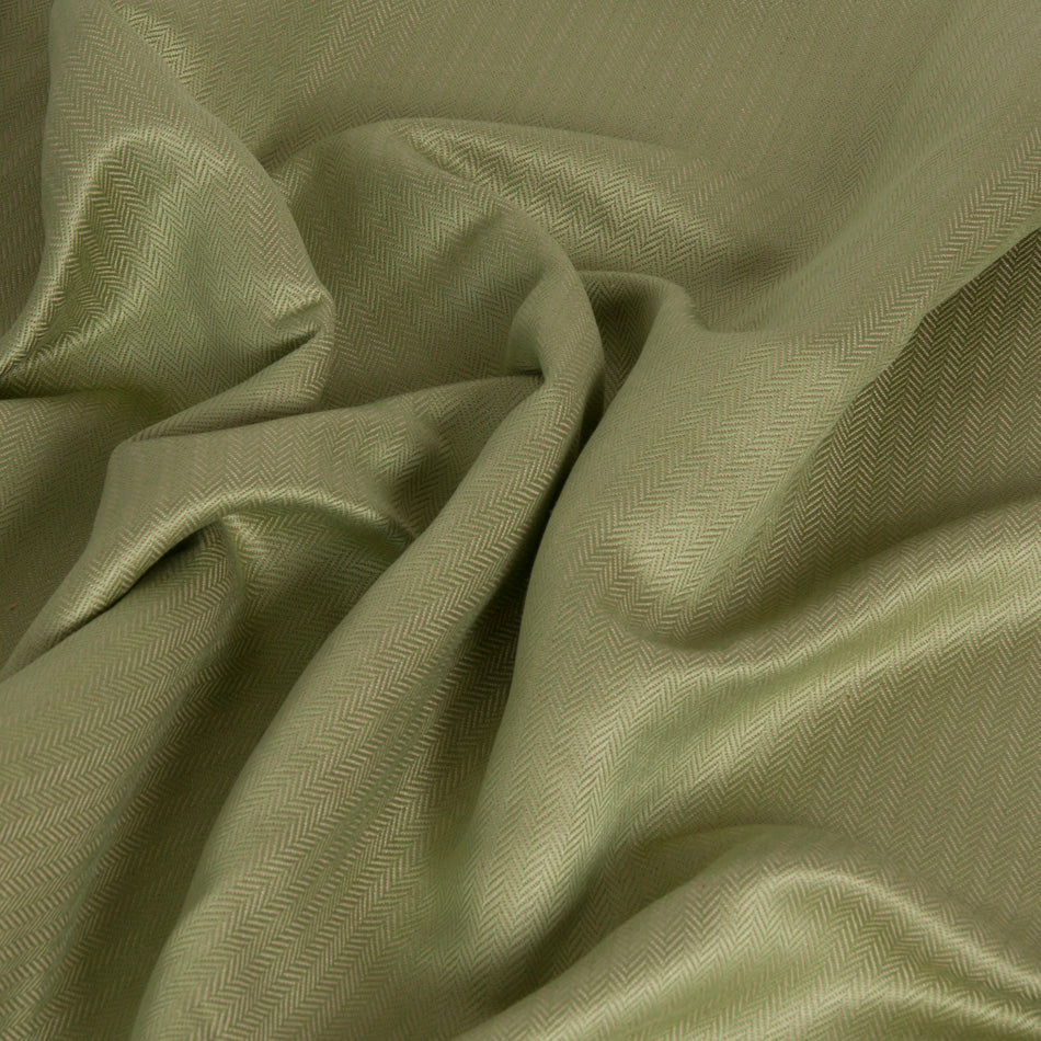 Wrinkled green herringbone fabric from a blend between linen and viscose, which resulted in a very soft material with luxurious hand, suited for cool, elegant and breathable summer clothing.