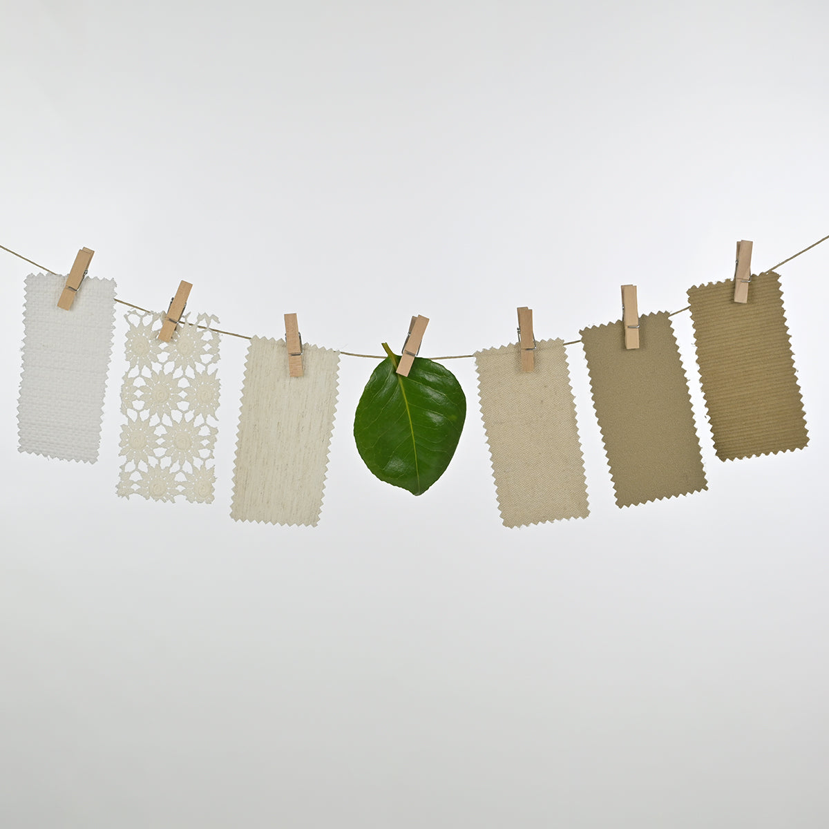 sustainability represented by six fabric samples attached to a wire with springs and a green leaf in the middle